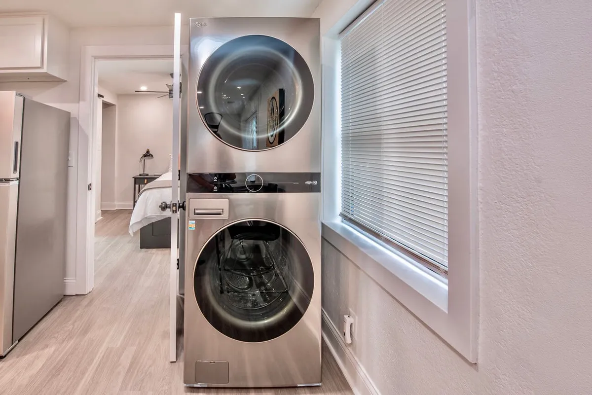 This image highlights a modern fridge adjacent to a stacked washer and dryer, illuminated by natural light from a nearby window. The scene emphasizes a clean, efficient, and contemporary vibe, suggesting a streamlined household workflow.